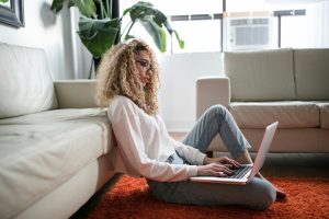 Writer curled up on the floor writing on laptop