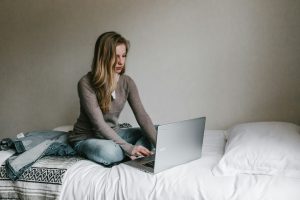Writer with laptop writing cozy in bed